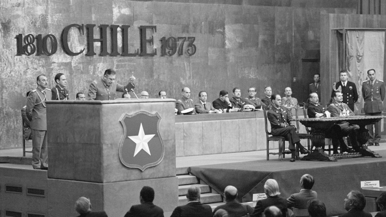 (Original Caption) 10/11/1973-Santiago, Chile- Military junta President General Augusto Pinochet (L) delivers a radio speech, on the one-month anniversary of the military coup that ousted President Salvador Allende.