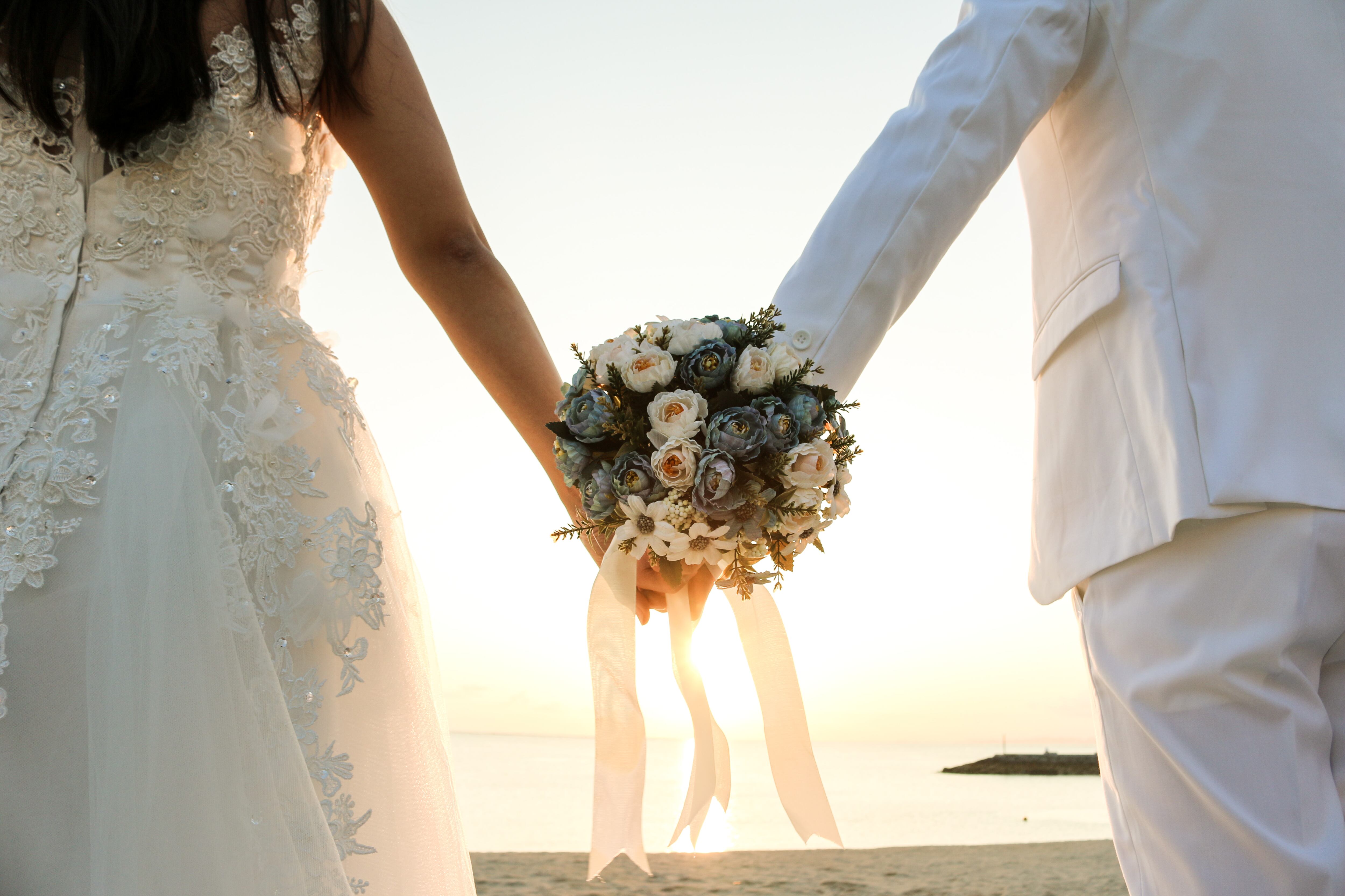 Pareja con un bouquet de rosas en matrimonio en la playa.