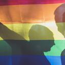 people, homosexuality, same-sex marriage, gay and love concept - close up of happy male gay couple hands over rainbow flag