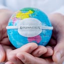 closeup of a caucasian doctor man holding a world globe with a protective mask with the word coronavirus written in it