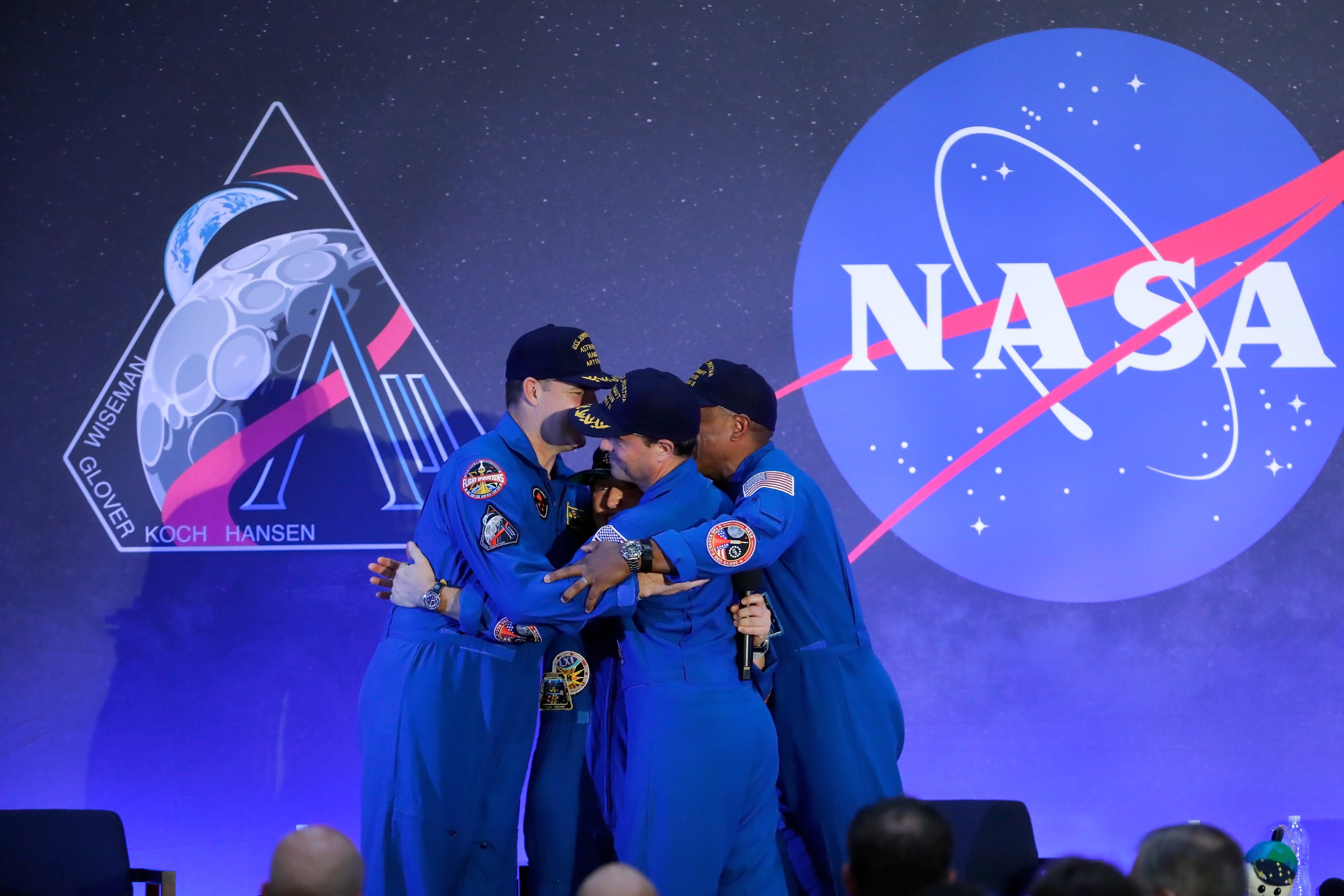 La tripulación del Artemis II, compuesta por Jeremy Hansen, Christina Koch, Reid Wiseman y Victor Glover, se abraza mientras conversan durante un acto de bienvenida en el aeropuerto Ellington Field de Houston.