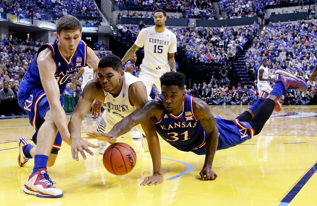 Karl-Anthony Towns, Sviatoslav Mykhailiuk y Jamari Traylor se lanzan por una bola perdida durante un partido de basquetbol universitario de la NCAA en Indianapolis, Estados Unidos. (AP)