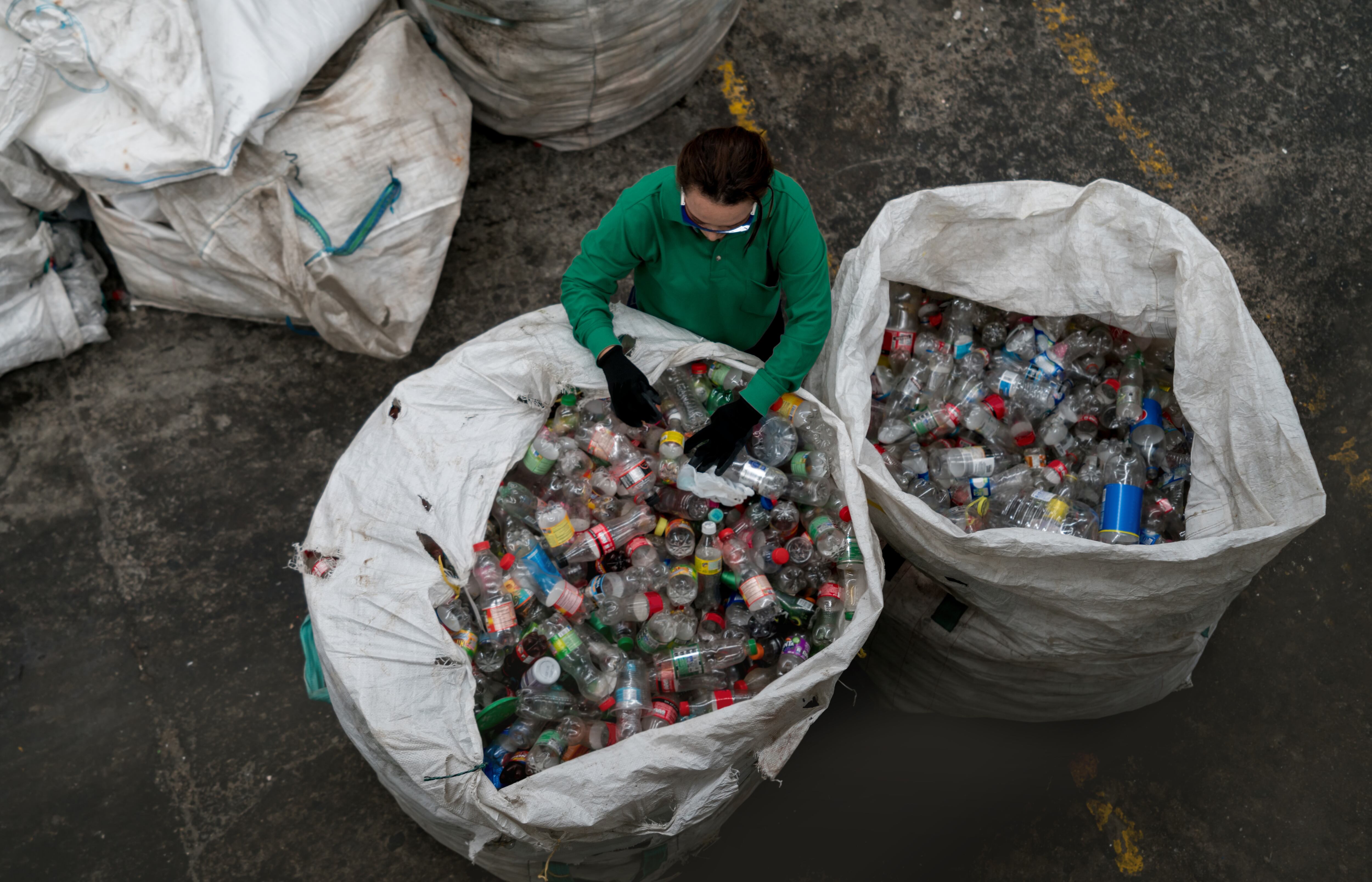 Woman working in a recycling center sorting some bottles and looking very happy - environmental concepts