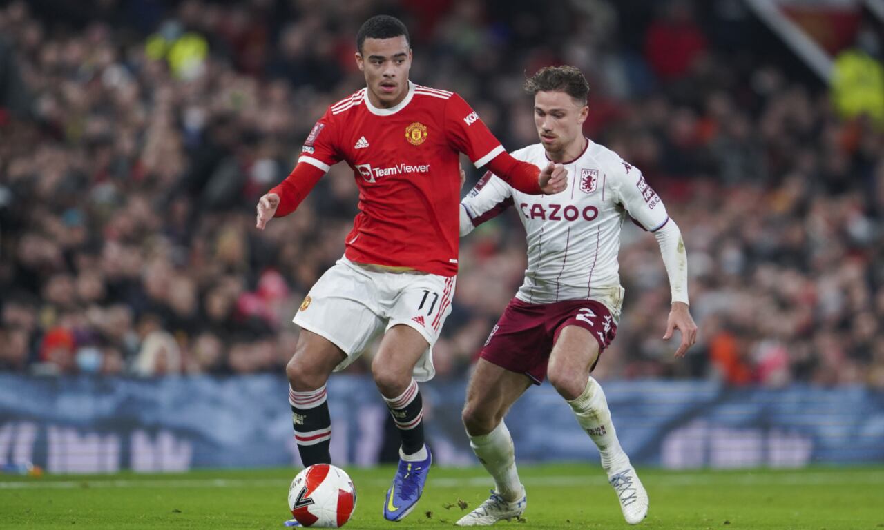 Manchester United's Mason Greenwood, left, plays the ball next to Aston Villa's Matty Cash during the English FA Cup third round soccer match between Manchester United and Aston Villa outside Old Trafford stadium in Manchester, England, Monday, Jan. 10, 2022. (AP Photo/Jon Super)