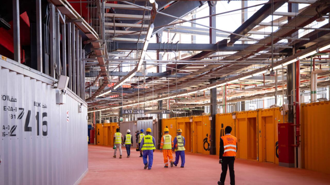30 de marzo de 2022, Catar, Doha: Los trabajadores caminan por un pasillo en el Estadio 974 durante una gira mediática de la FIFA. Se utilizaron 974 contenedores de transporte dispuestos en colores vivos para construir el estadio. Foto: Christian Charisius/dpa (Photo by Christian Charisius/picture alliance via Getty Images)