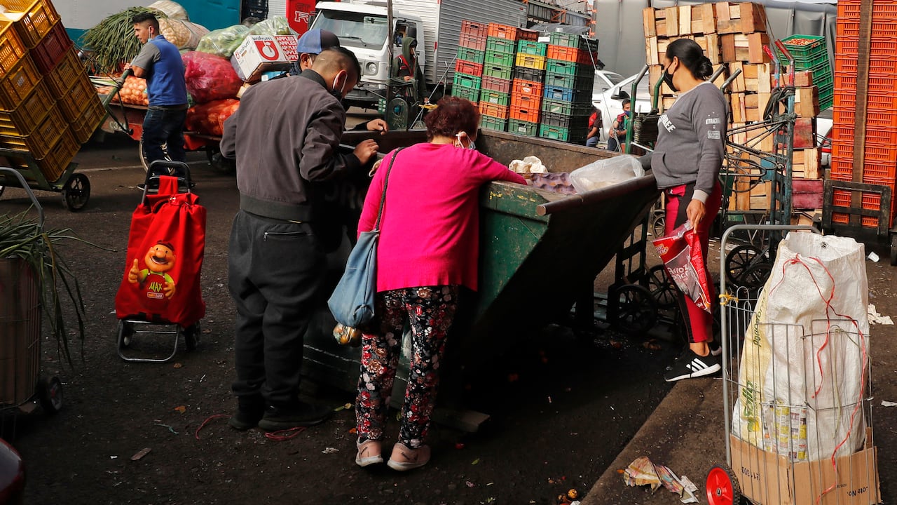 Familias buscan en los contenedores de desperdicios orgánicos algo para llevar a su mesa, en Corabastos