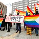 Abogados de los demandantes y partidarios posan con banderas arco iris, símbolo de la comunidad LGBTQ, y un cartel con el lema "Fallo inconstitucional" en el exterior del tribunal de distrito de Sapporo tras un juicio, en Sapporo, en el norte de Japón, el 17 de marzo de 2021. (Yohei Fukai/Kyodo News via AP)