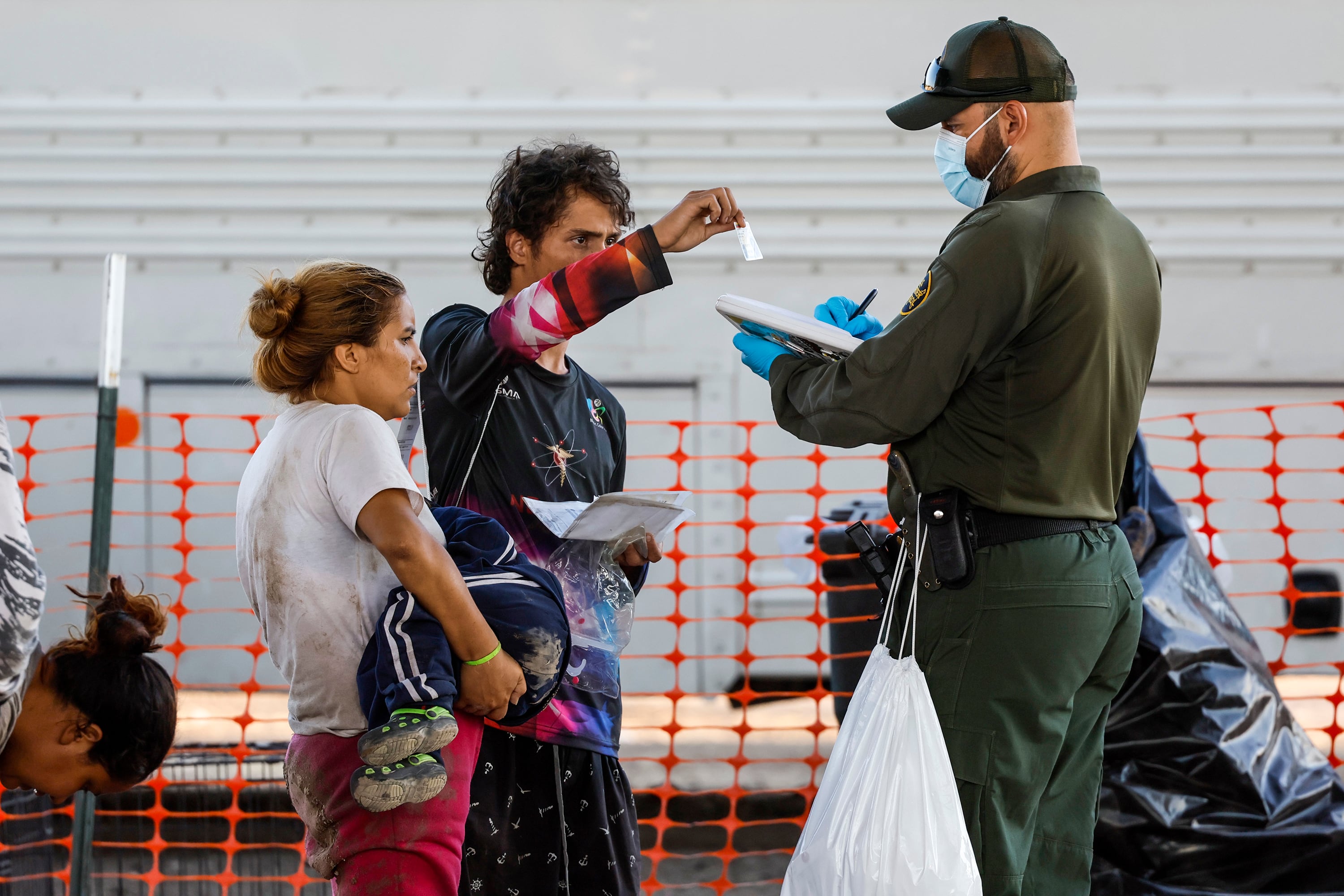 un agente de la Patrulla Fronteriza toma información de una familia en un lugar de procesamiento ubicado a orillas del Río Grande.