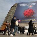 Personas que usan máscaras faciales como precaución contra el coronavirus caminan bajo una pancarta que enfatiza una campaña de distanciamiento social mejorada frente al Ayuntamiento de Seúl en Seúl, Corea del Sur, el 25 de noviembre de 2020. La pancarta dice: "Tenemos que parar antes de que COVID-19 detenga todo ". El orbe espinoso está en todos los sitios médicos y de noticias. Está en toda la televisión y en los folletos para la limpieza de automóviles COVID. Foto: AP / Ahn Young-joon, archivo.