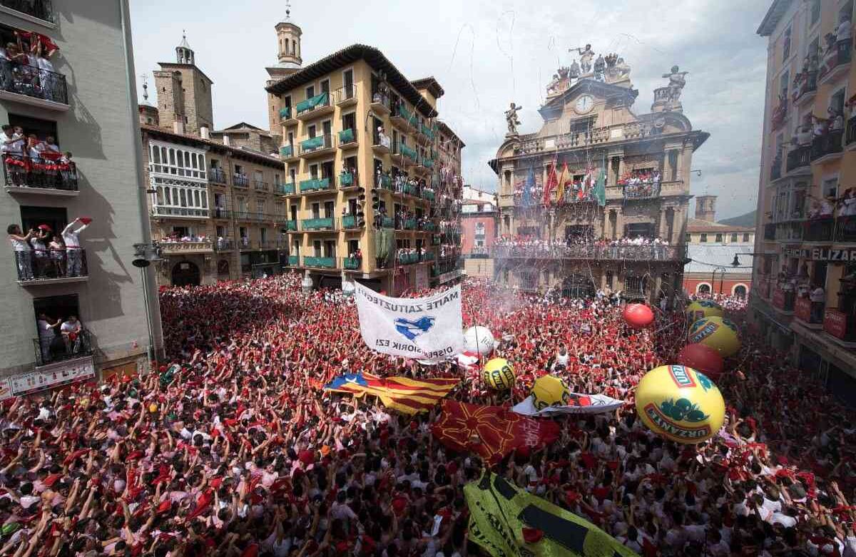 Los participantes llevan pañuelos rojos mientras celebran el 'Chupinazo' para marcar el inicio del pistoletazo de salida al mediodía del Festival de San Fermín, frente al Ayuntamiento de Pamplona, al norte de España / AFP PHOTO / ANDER GILLENEA