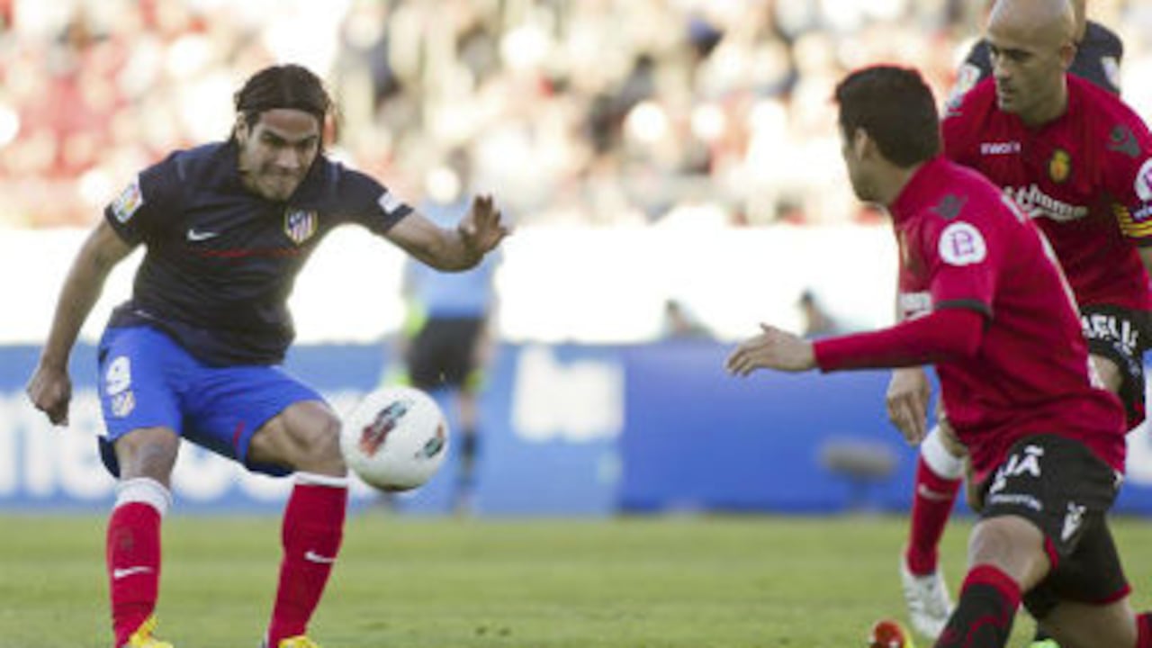 El delantero colombiano del Atlético de Madrid Radamel Falcao (i) marca de vaselina ante los defensas del RCD Mallorca José Carlos de Araujo Nunes (d) y Pablo Cáceres.
