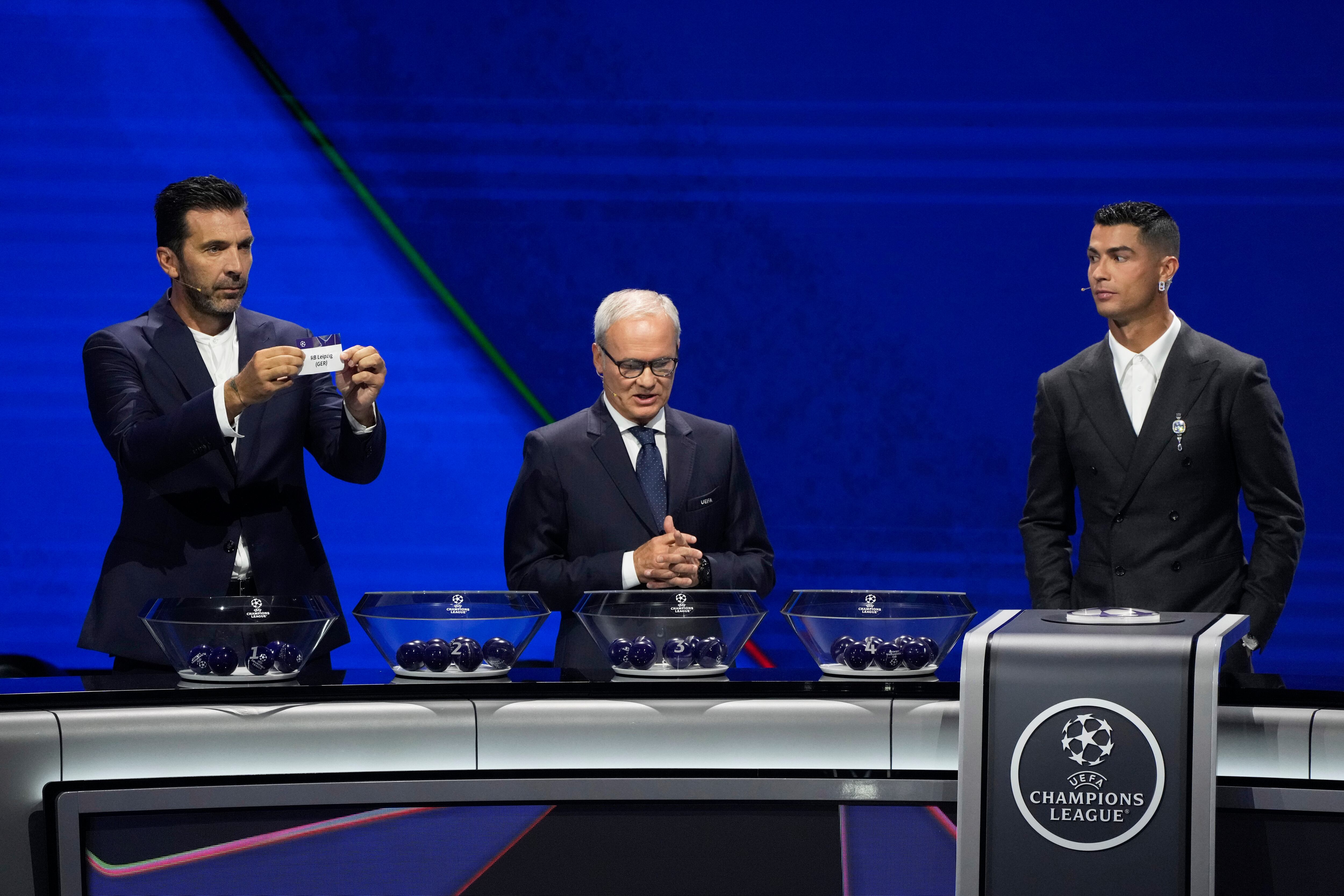 Former Italian goalkeeper Gianluigi Buffon holds a ticket for Leipzig next to UEFA's Giorgio Marchetti and player Cristiano Ronaldo, from left, during the Champions League, league phase, draw, in Monaco, Thursday, Aug. 29, 2024. (AP Photo/Gregorio Borgia)