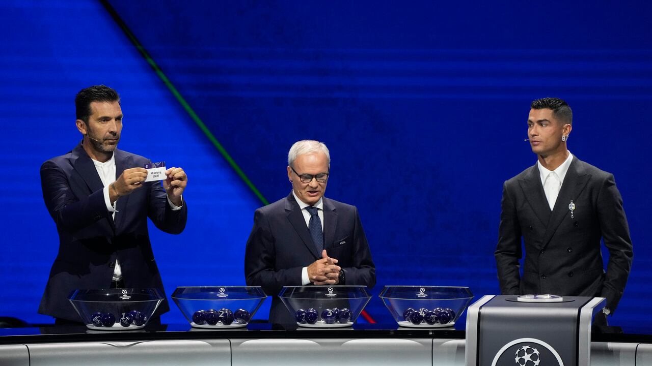 Former Italian goalkeeper Gianluigi Buffon holds a ticket for Leipzig next to UEFA's Giorgio Marchetti and player Cristiano Ronaldo, from left, during the Champions League, league phase, draw, in Monaco, Thursday, Aug. 29, 2024. (AP Photo/Gregorio Borgia)