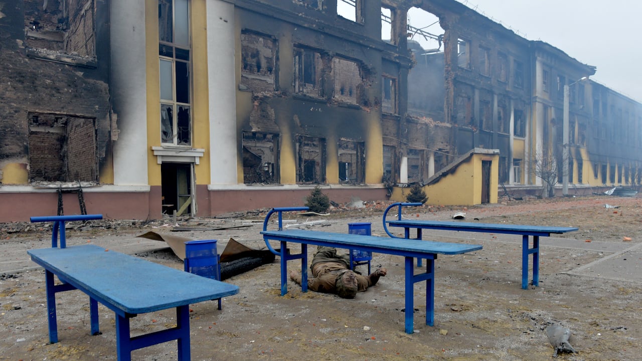 El cuerpo de un soldado ruso yace afuera de una escuela destruida como resultado de una pelea no lejos del centro de la ciudad ucraniana de Kharkiv. (Foto por Serguéi BOBOK / AFP)