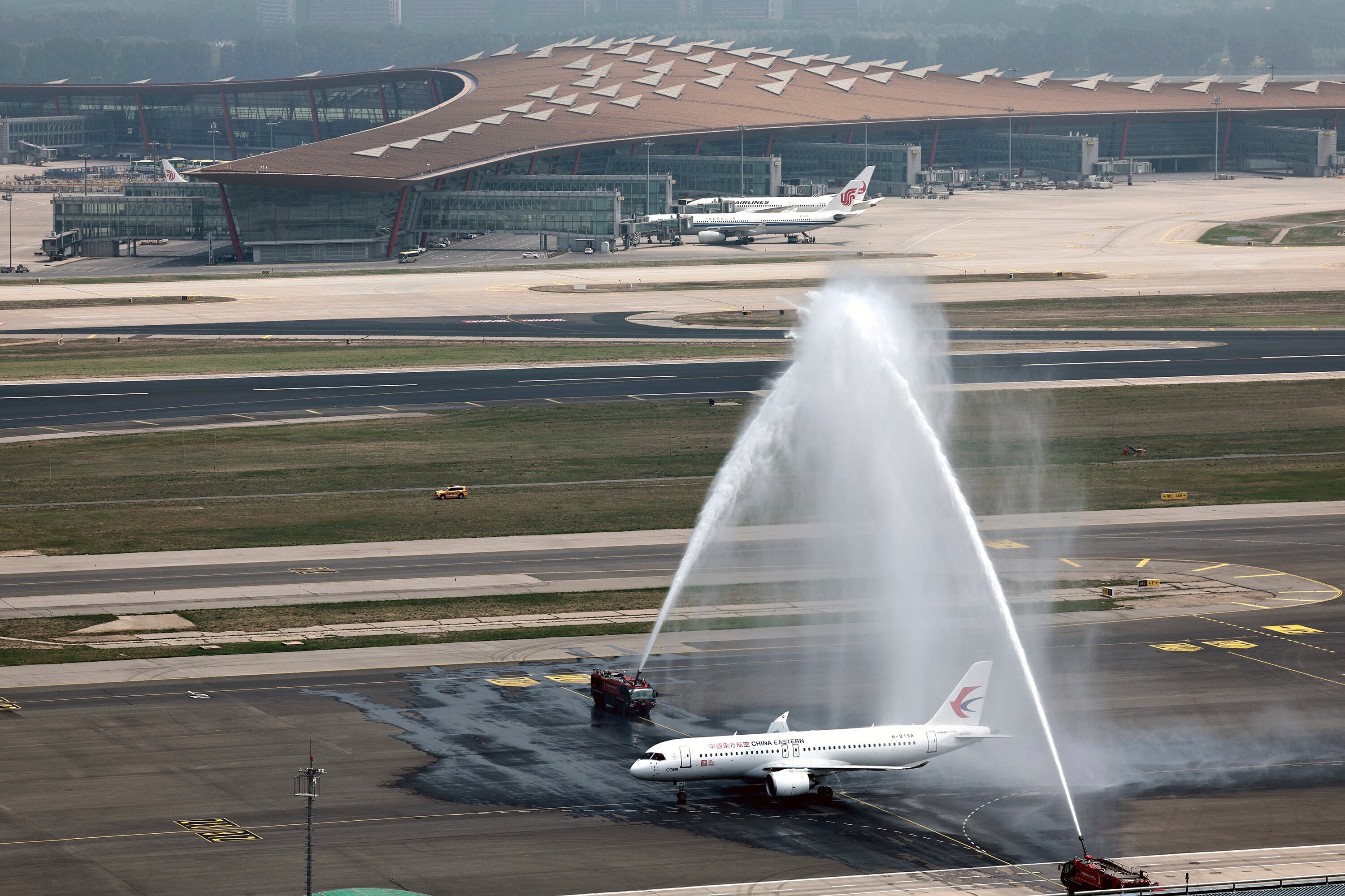 En esta foto publicada por la Agencia de Noticias Xinhua, un avión C919, el primer avión de pasajeros de fabricación nacional de China es recibido con chorros de agua después de completar su primer vuelo comercial operado por China Eastern Airlines en el Aeropuerto Internacional de Beijing