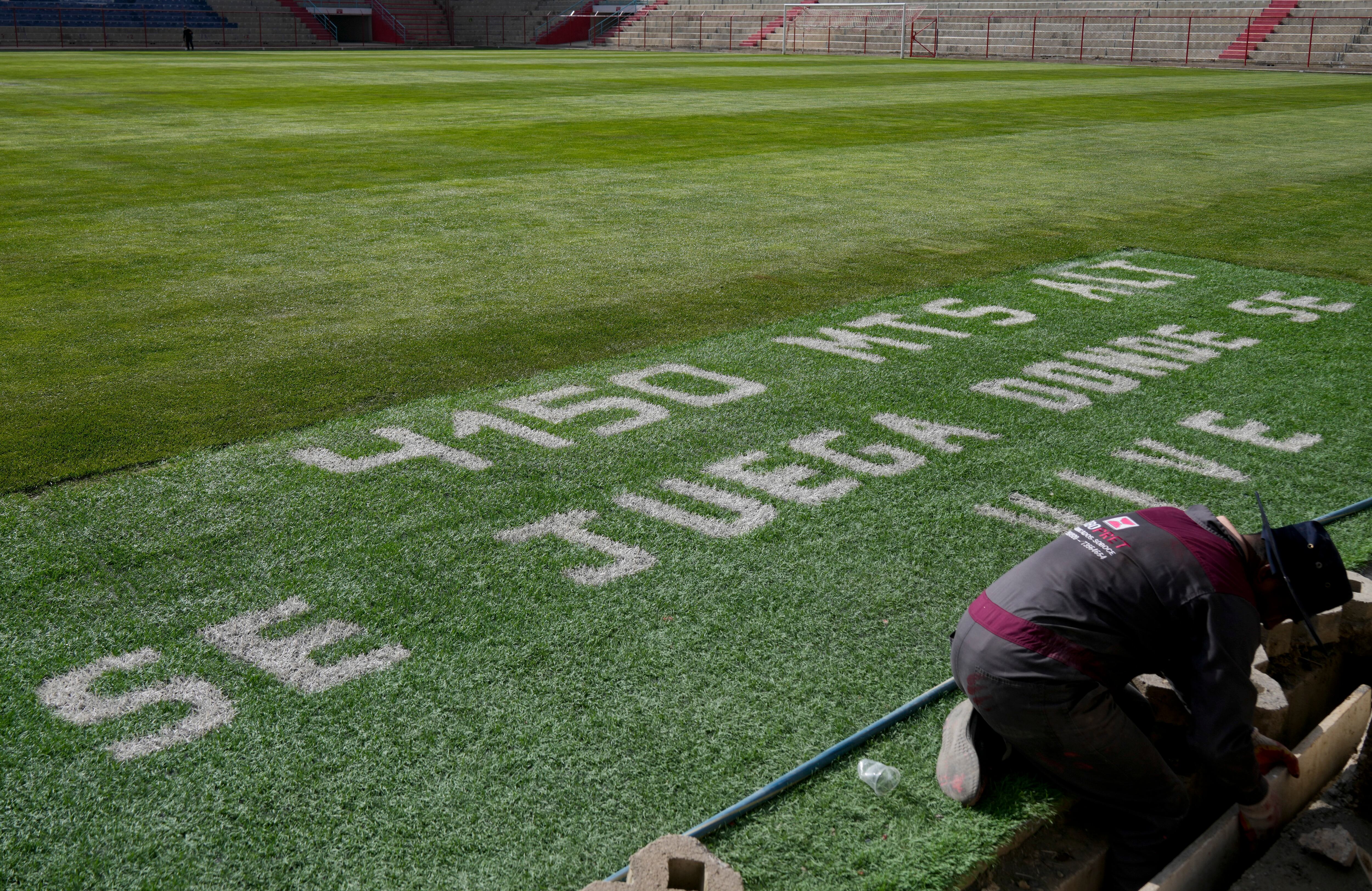 The field at the Municipal Villa Ingenio Stadium is covered with the Spanish phrase: "4,150 meters above sea level. You play where you live" in El Alto, Bolivia, Thursday, Aug. 29, 2024. (AP Photo/Juan Karita)