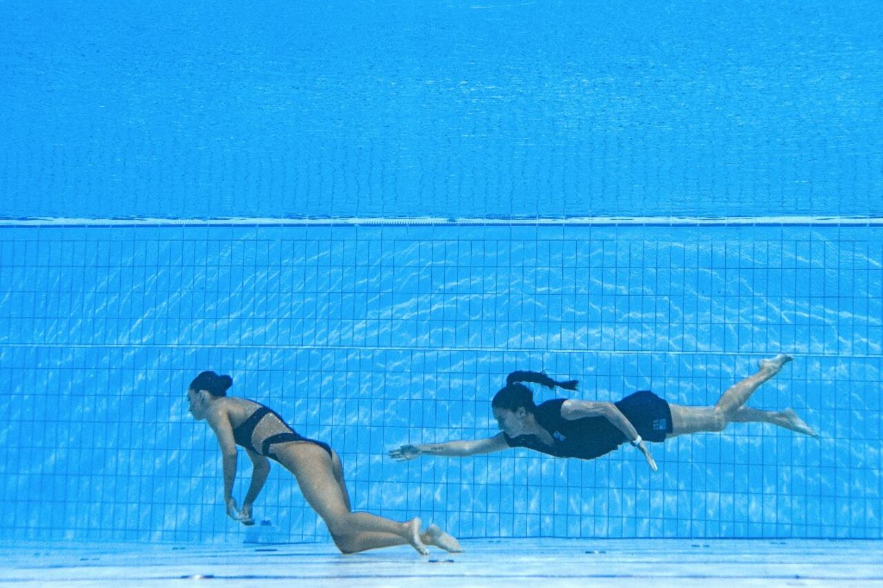 Andrea Fuentes, integrante española del Equipo de Natación de Estados Unidos, nada para recuperar a Anita Alvarez, estadounidense integrante de su grupo, del fondo de la piscina durante un incidente en las finales de natación artística libre femenina en solitario. Sucedió durante el Campeonato Mundial Acuático de Budapest 2022, en el Complejo de Natación Alfred Hajos en Budapest (Hungría) el 22 de junio de 2022 (Foto de Oli SCARFF / AFP)