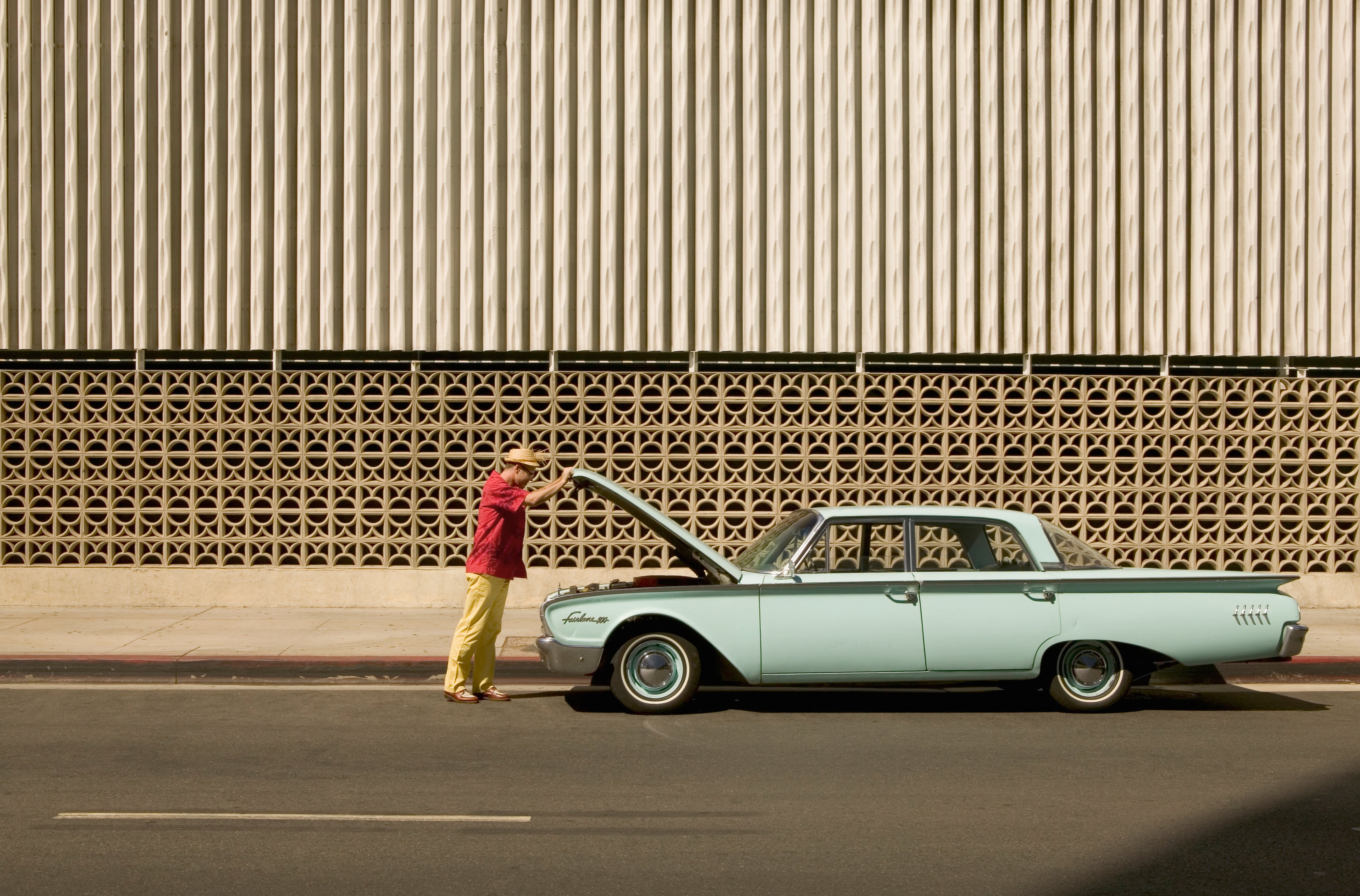 Persona revisando la parte del motor de su vehículo. Imagen de referencia.