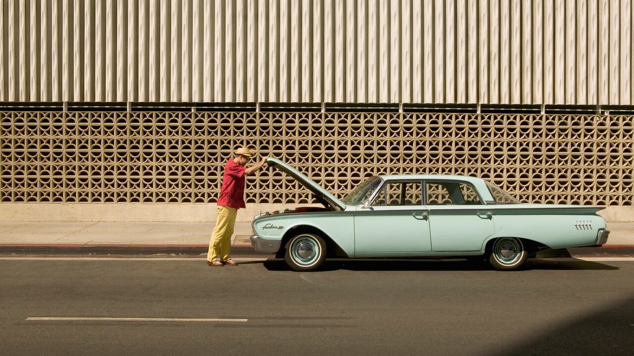 Persona revisando la parte del motor de su vehículo. Imagen de referencia.