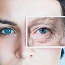Young woman with photo of aged eye over her own