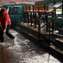 El asistente de la casa club de los St. Louis Cardinals, Andrew Rettig, intenta despejar un desagüe en el dugout inundado de los Cardinals durante un retraso por lluvia en el primer juego de una doble cartelera de béisbol entre los Cardinals y los New York Yankees