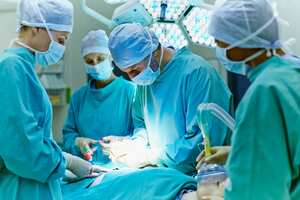Group of surgeons performing surgery on patient in operating room