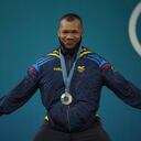 Silver medalist Yeison Lopes of Colombia celebrates on the podium during the medal ceremony for the men's 89kg weightlifting event at the 2024 Summer Olympics, Friday, Aug. 9, 2024, in Paris, France. (AP Photo/Kin Cheung)