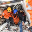Rescatistas sacan a un herido debajo de un edificio derrumbado por el terremoto en Indonesia.