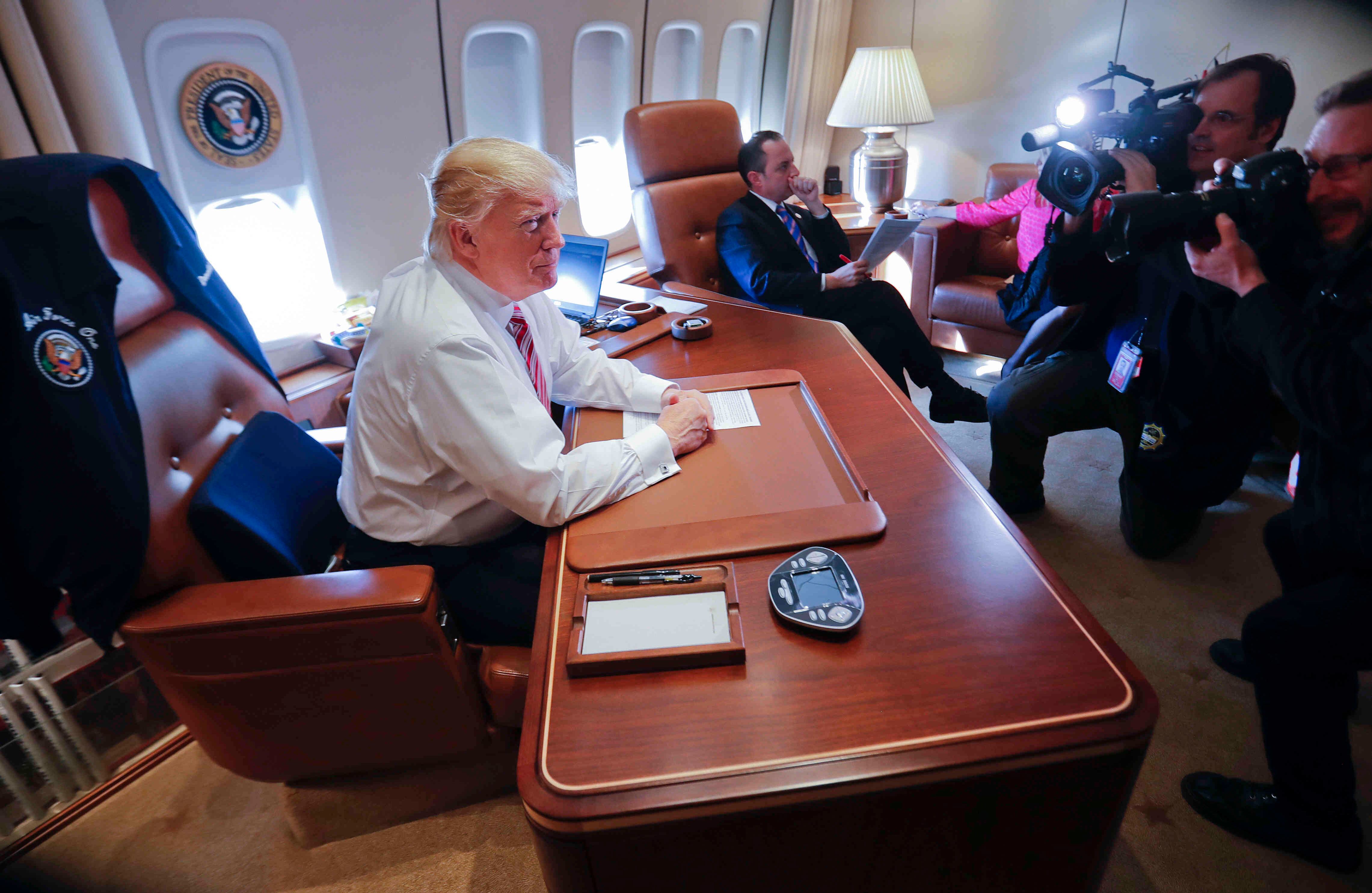 El Presidente Donald Trump se sienta en su escritorio dentro del Air Force One al llegar a la Base Aérea de Andrews. En el centro está el Jefe de Gabinete de Trump Reince Priebus. El jueves 26 de enero de 2017. (Foto AP / Pablo Martínez Monsiváis)