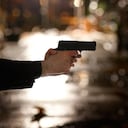 Man pointing gun on city street.