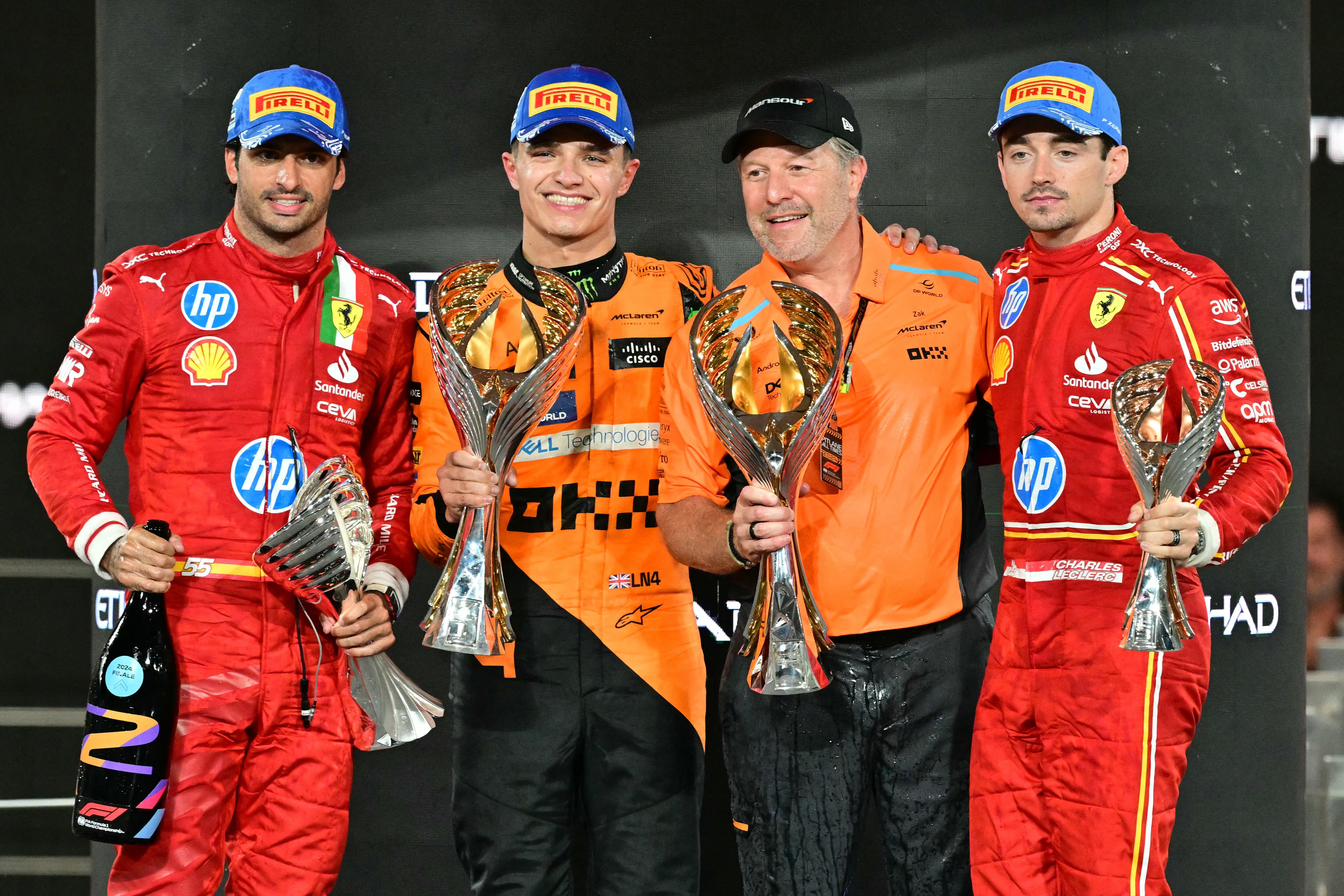 (De izquierda a derecha) El piloto español de Ferrari, Carlos Sainz Jr., el piloto británico de McLaren, Lando Norris, el director estadounidense de McLaren, Zak Brown, y el piloto monegasco de Ferrari, Charles Leclerc, celebran en el podio tras el Gran Premio de Fórmula Uno de Abu Dabi en el circuito Yas Marina de Abu Dabi. 8 de diciembre de 2024. (Foto de Giuseppe CACACE / AFP)