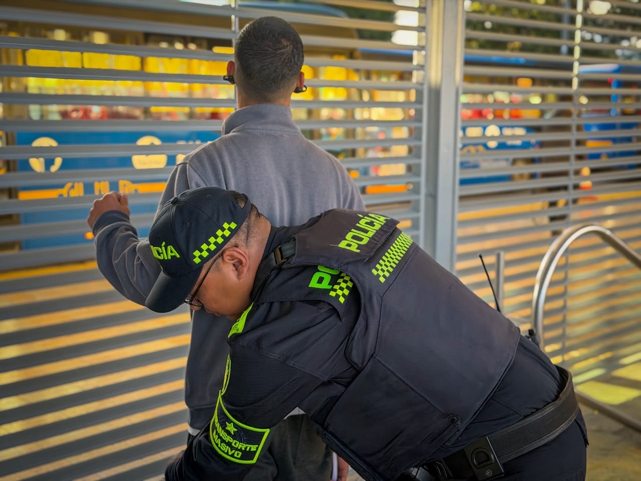 Uniformado de la policía realizando una requisa a un usuario de TransMilenio.