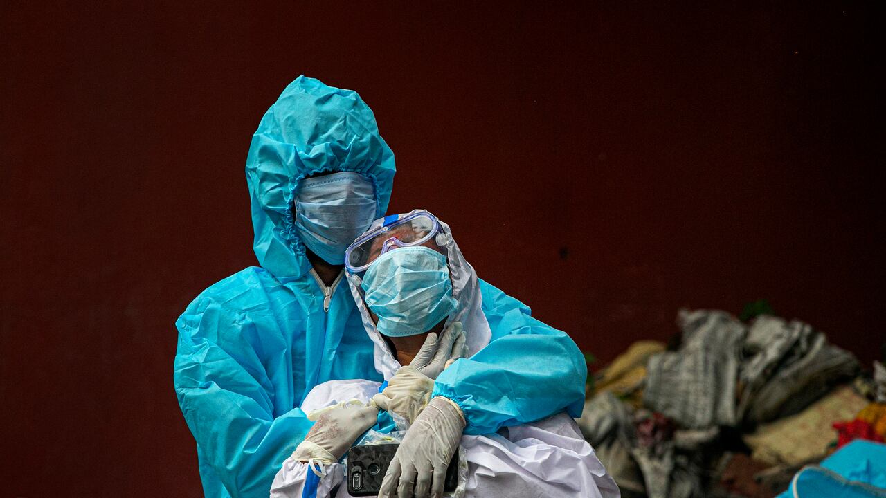 Una mujer india vestida con equipo protector blanco está de luto después de vislumbrar el cuerpo de su esposo, víctima de COVID 19, en un campo de cremación en Gauhati, India, el jueves 10 de septiembre de 2020. India informó de otro aumento récord de 95.735 nuevas infecciones por coronavirus en las últimas 24 horas a medida que el virus se propaga más allá de sus principales ciudades. El ministerio dijo que el aumento de nuevas infecciones se debe al aumento de las pruebas diarias que supera el millón ahora. Sin embargo, los expertos advierten que el brote de India está entrando en una fase más peligrosa a medida que el virus se propaga a ciudades y pueblos más pequeños. (Foto AP / Anupam Nath)