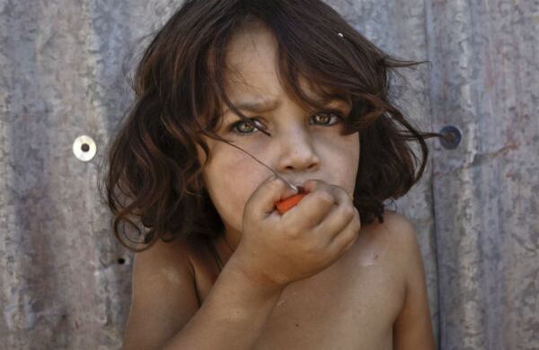 Una niña refugiada siria come un tomate en el pueblo de Al-Faour, Líbano, cerca de la frontera con Siria. (AP) 