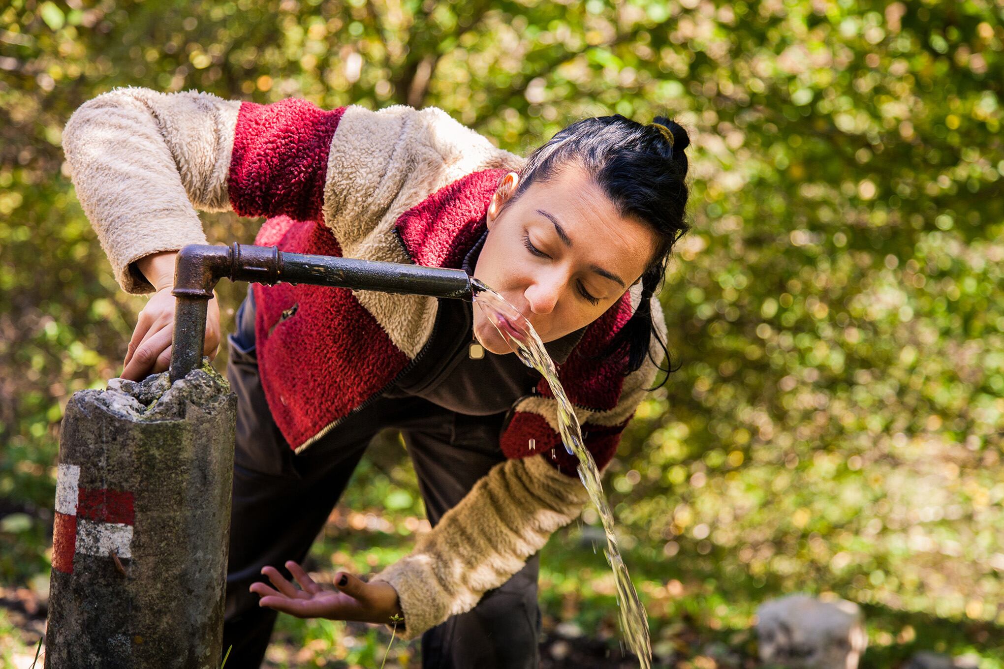 Fuente de agua en una montaña. Agua natural. Mujer tomando agua
