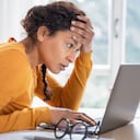 Close up color image depicting a mid adult man checking his groceries bill in the supermarket after making his purchases at the checkout. Focus on the man with the supermarket checkout defocused in the background. The man is wearing a casual blue polo shirt and has a worried expression on his face.