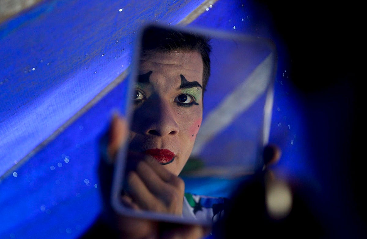 El payaso de Jumbo Circus Franklin Parada, de 22 años, se maquilla para su entrenamiento, a pesar de que el circo ha estado cerrado durante cuatro meses en El Alto, Bolivia. Para sobrevivir, Parada gana dinero descargando bolsas de arroz de camiones en una feria callejera. Foto: Juan Karita / AP