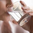 Cerrar hermosa mujer sedienta bebiendo agua mineral pura, sosteniendo un vaso en la mano, atractiva joven disfrutando de agua limpia, estilo de vida saludable y concepto de refresco, belleza natural