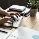 Hombre de negocios de cerca usando una computadora portátil, escribiendo en el teclado, sentado en un escritorio de madera con documentos, escribiendo un correo electrónico, contable escribiendo un informe financiero, estudiante ocupado estudiando en línea, buscando información