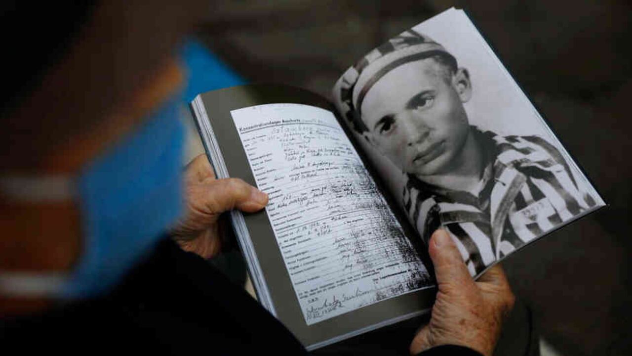 El sobreviviente, Shalom Stamberg, sostiene un libro con su foto de cuando era prisionero del campo de concentración de Auschwitz.