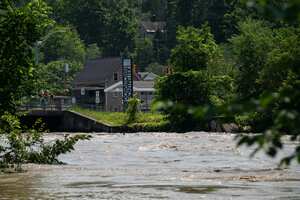 Un letrero que da la bienvenida a los visitantes al centro de Montpelier se ve detrás del río Winooski inundado el 11 de julio de 2023.
