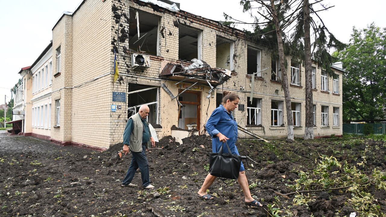Los residentes locales pasan junto a un edificio dañado parcialmente destruido después de un bombardeo en la ciudad de Chuguiv, al este de Kharkiv, el 16 de julio de 2022. - En la región noreste alrededor de Kharkiv, la segunda ciudad de Ucrania, el gobernador Oleg Synegubov dijo que un ataque nocturno con misiles rusos mató tres personas en el pueblo de Chuguiv. (Foto de SERGEY BOBOK / AFP)