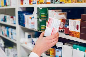 Una joven farmacéutica coloca los medicamentos en los estantes de la farmacia y hace un inventario.