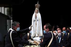 A woman outside the chapel "Capelinha das Aparicoes" looks at a man carrying a cross at Fatima, central Portugal, on May 11, 2017. Two of the three child shepherds who reported apparitions of the Virgin Mary in Fatima, Portugal, one century ago, will be declared saints on May 13, 2017 by Pope Francis.
The canonisation of Jacinta and Francisco Marto will take place during the Argentinian pontiff's visit to a Catholic shrine visited by millions of pilgrims every year. (Photo by PATRICIA DE MELO MOREIRA / AFP)