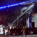 Los bomberos trabajando para extinguir el incendio en un inmueble después de que la avioneta se estrellara.