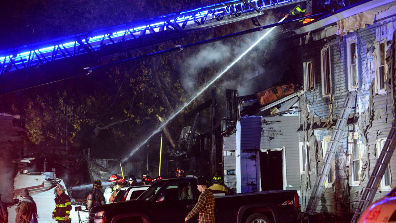 Los bomberos trabajando para extinguir el incendio en un inmueble después de que la avioneta se estrellara.