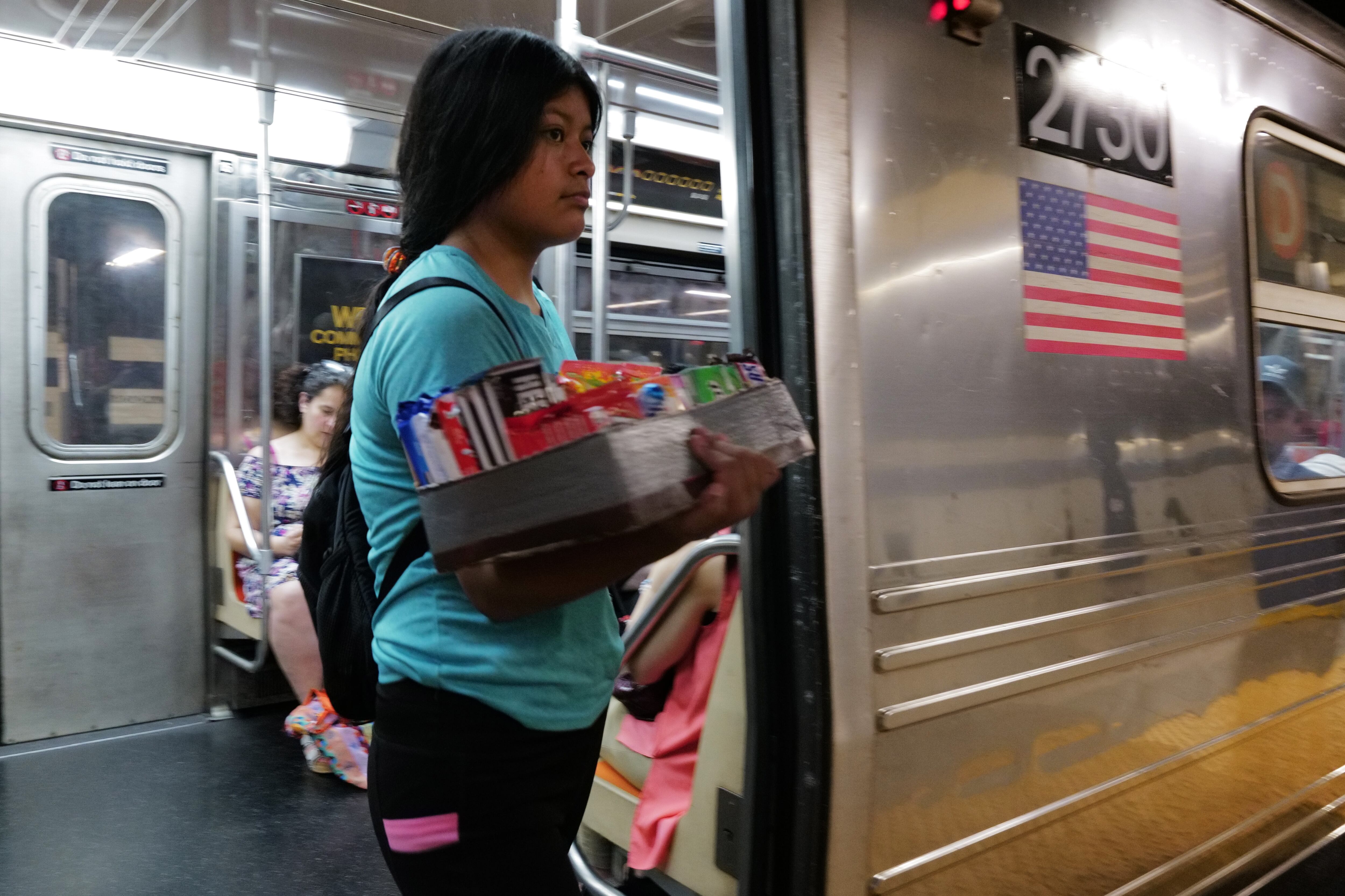 Un adolescente vende dulces y otros artículos en un vagón del metro de la ciudad de Nueva York el 18 de agosto de 2023 en la ciudad de Nueva York. Más de 70.000 solicitantes de asilo han llegado a la ciudad de Nueva York desde el año pasado, según el Ayuntamiento, y muchos se han dedicado a vender artículos en las calles y el metro de la ciudad.