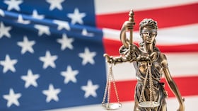 La estatua de la justicia, diosa de la justicia frente a la bandera americana.