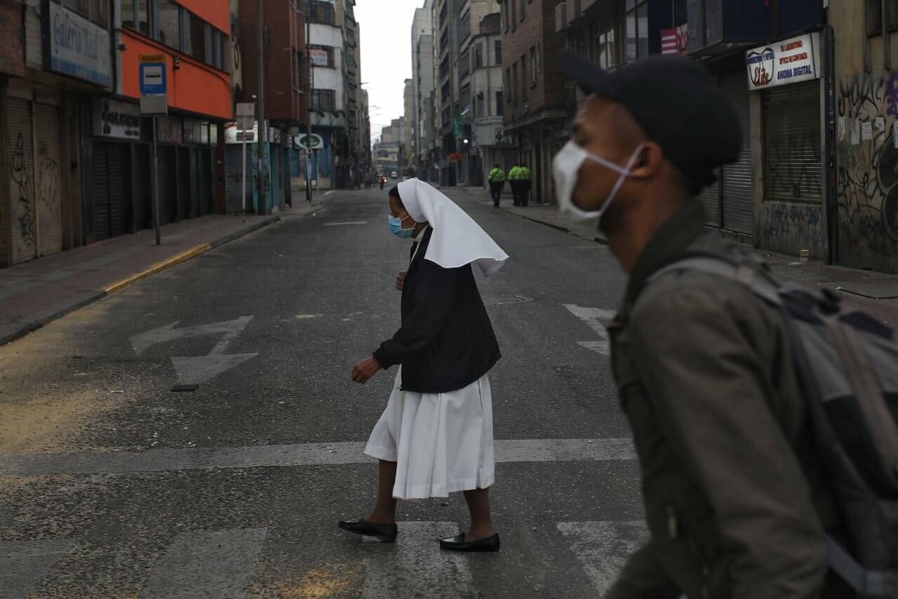 Una religiosa atraviesa la calle sin ningún vehículo en el momento, a lo lejos unos agentes de Policía monitorean la jornada. Foto: Esteban Vega/ Semana