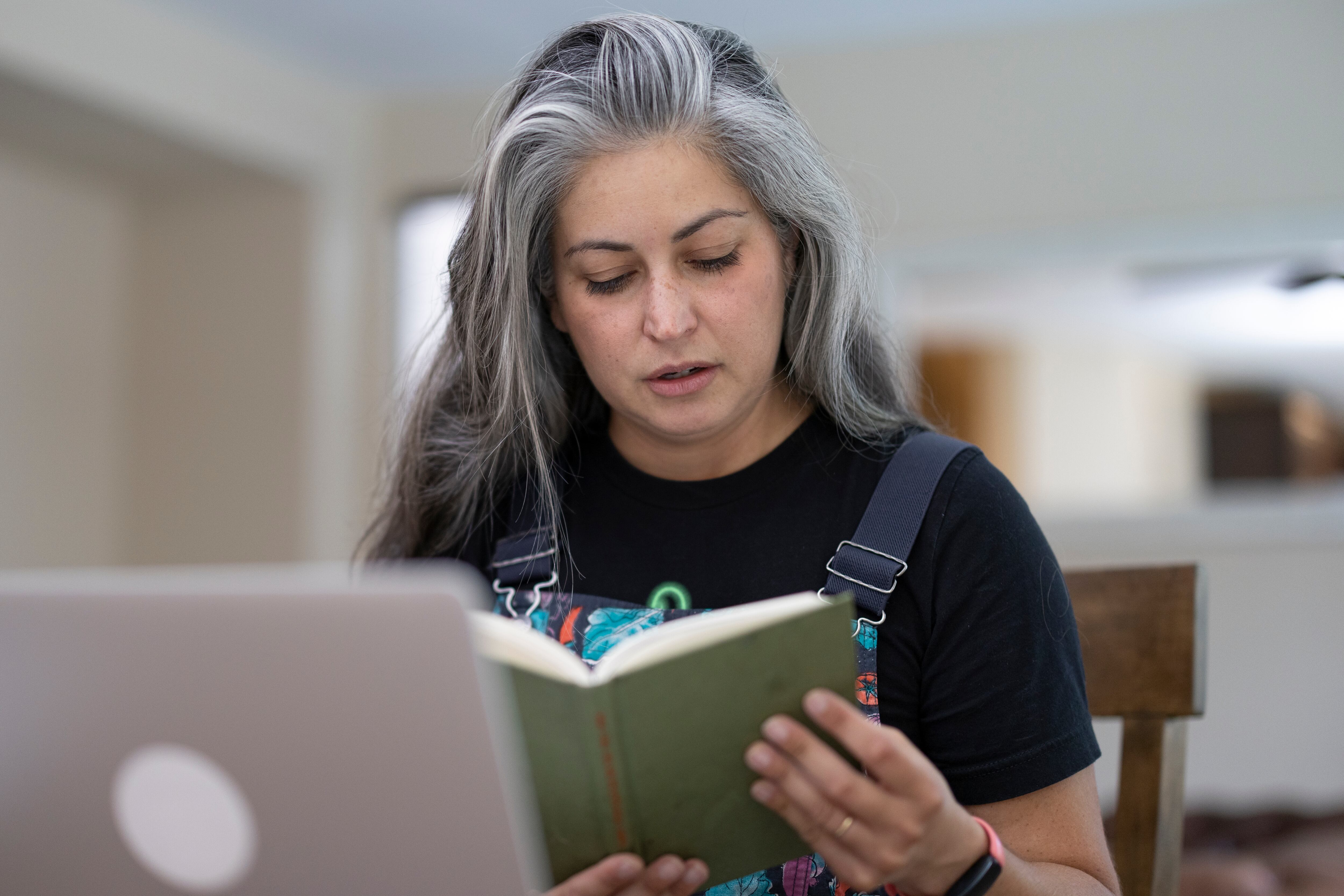 A woman in her 40's using a laptop for online learning at home